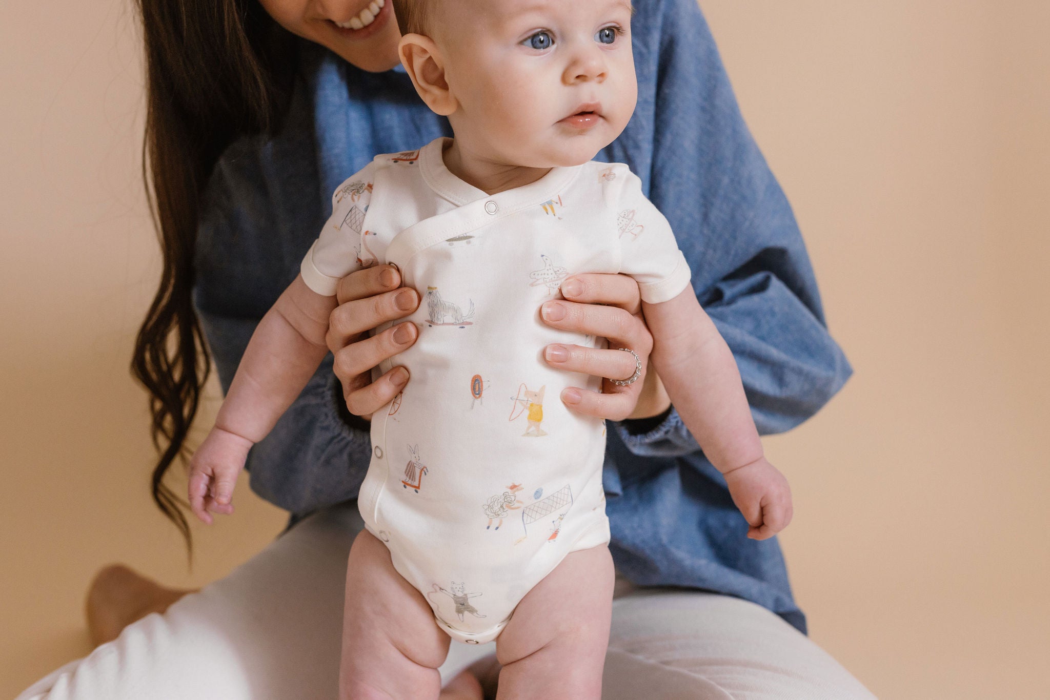 A mom holds her baby in front of her.