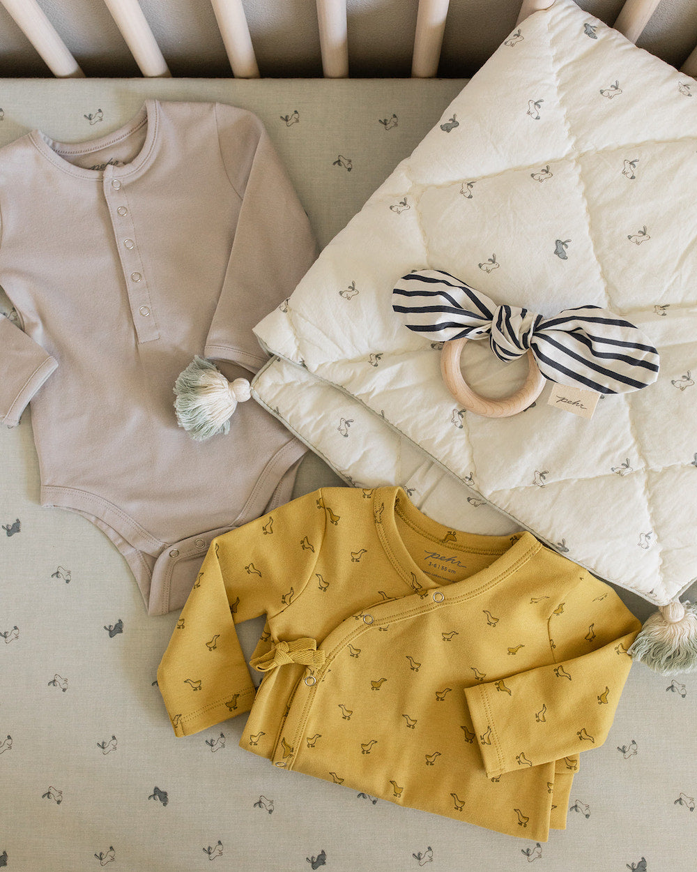 baby onesies, blanket and teething ring in crib