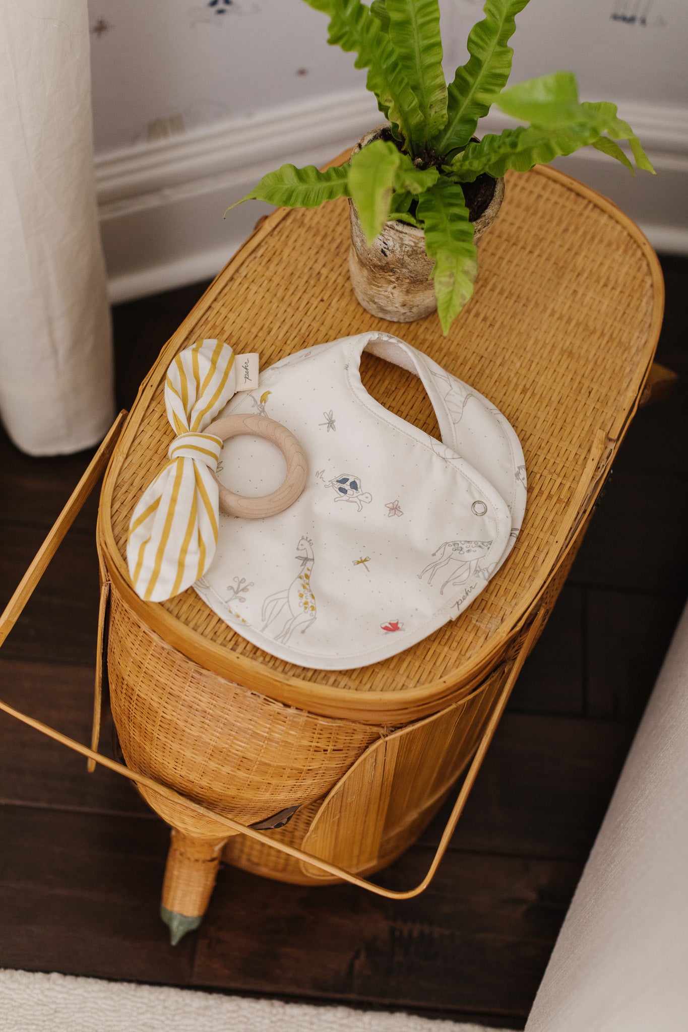 Pehr Bib and Teether laying on rattan basket