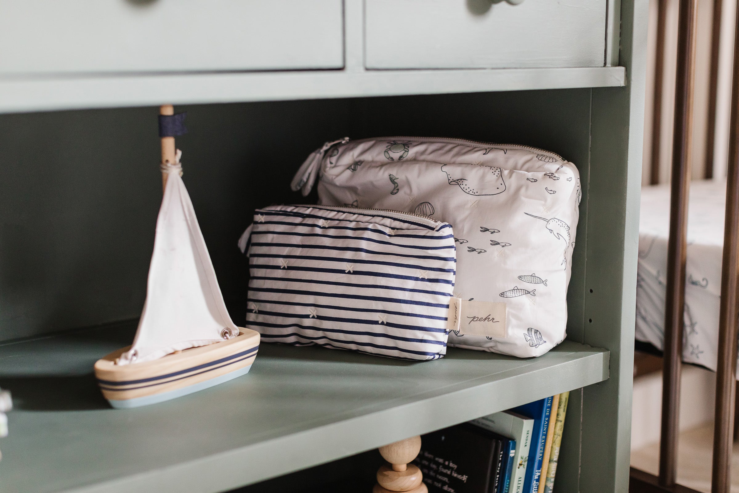 Pehr On The Go Pouch & Mini Pouch on shelf next to toy sailboat