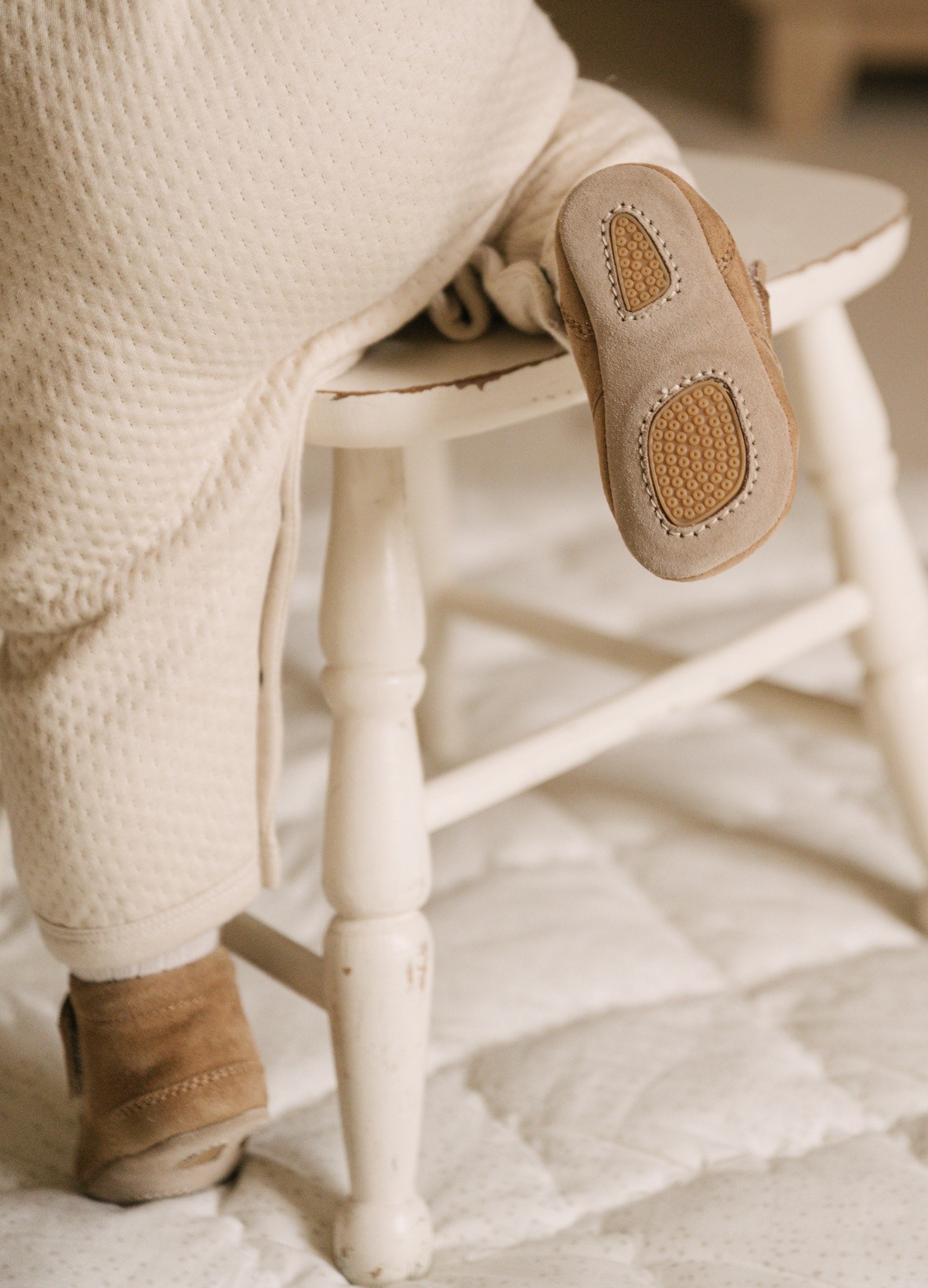 Image of baby trying to climb on a chair wearing Pehr baby booties