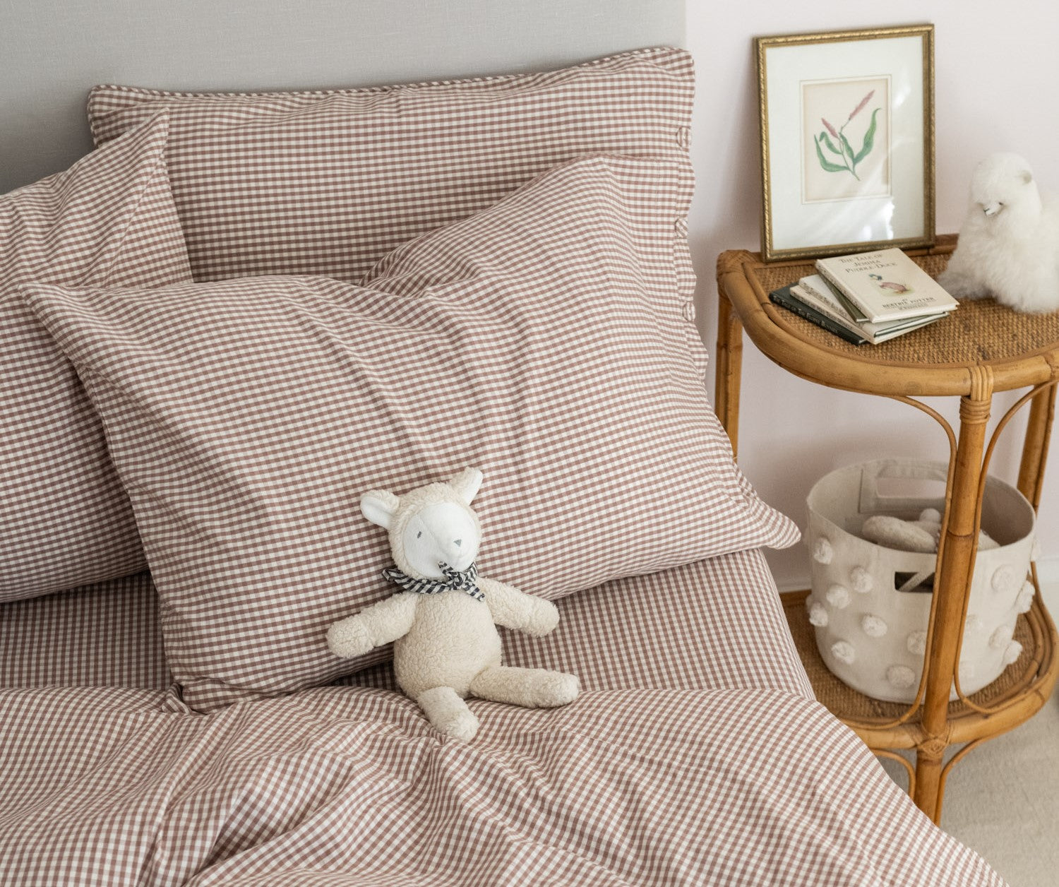 Overhead shot of twin bed with pink gingham toddler bedding and nightstand beside