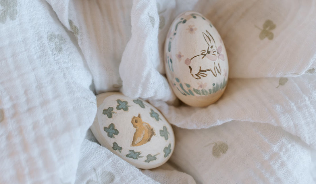 Two hand-painted eggs sit on a clover swaddle. 