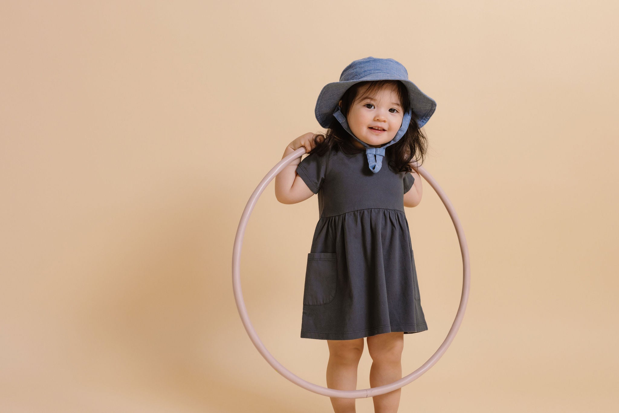 A little girl stands with a hula hoop, wearing a Garment Dye Playground Dress