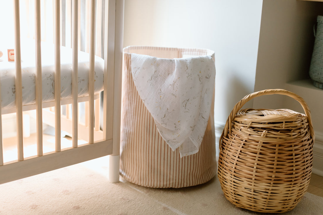 An image of a nursery with a striped hamper and swaddle.
