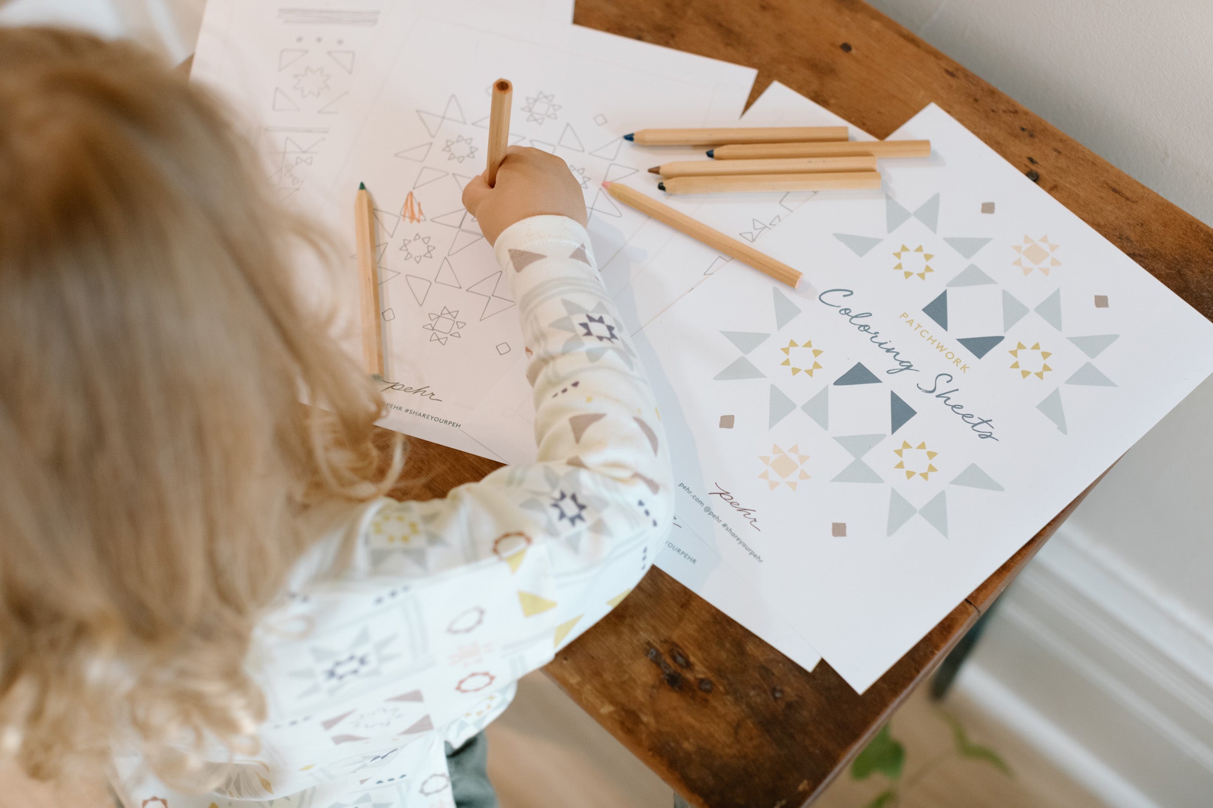 Child wearing patchwork shirt coloring in a color sheet