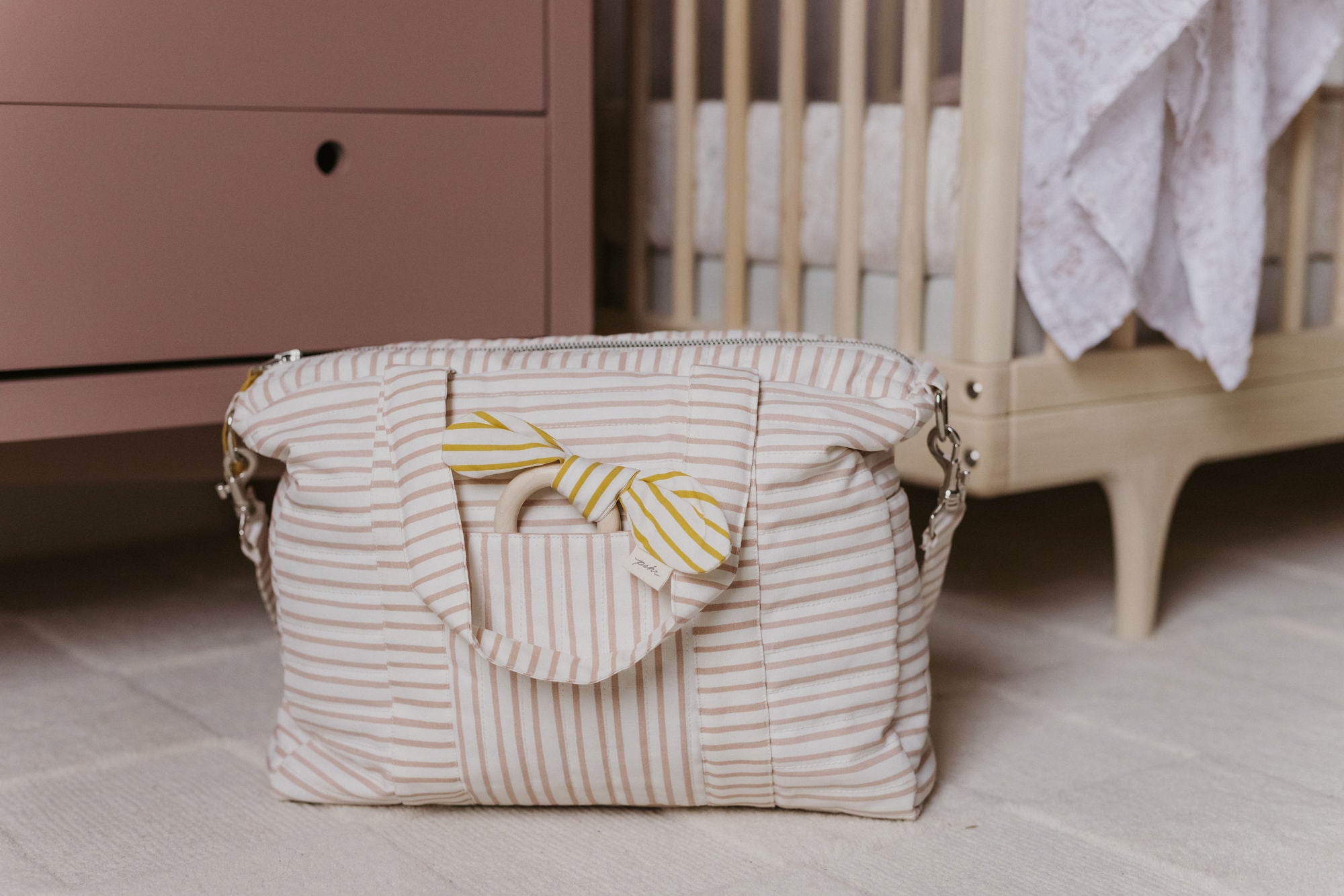 Diaper Bag on floor of nursery with Teether tucked in front pocket