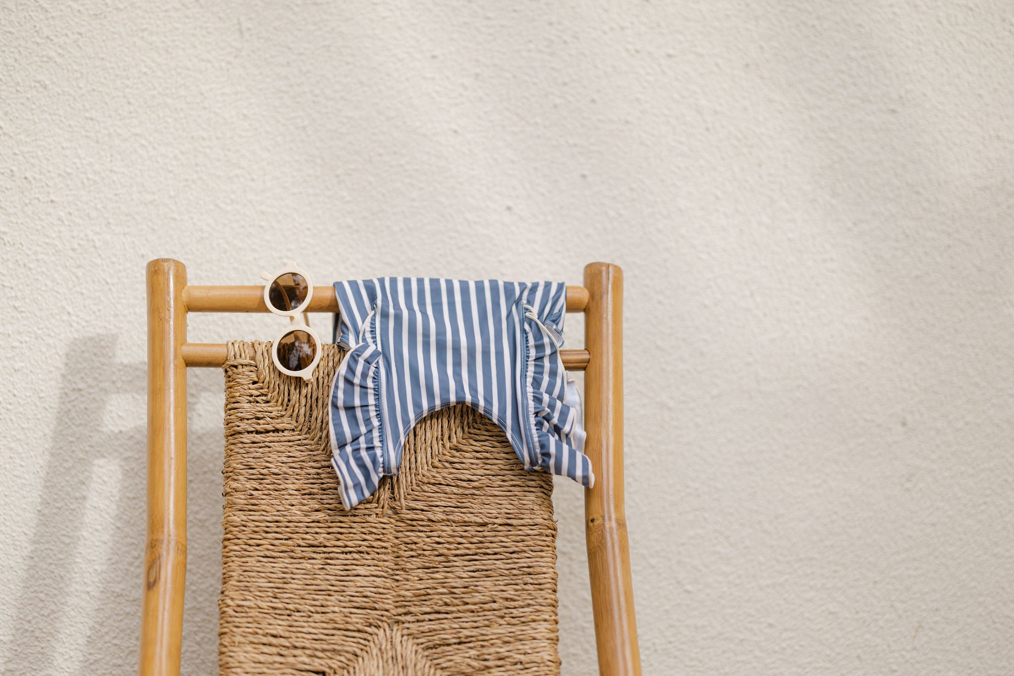 Baby swim suit hanging over woven wooden chair