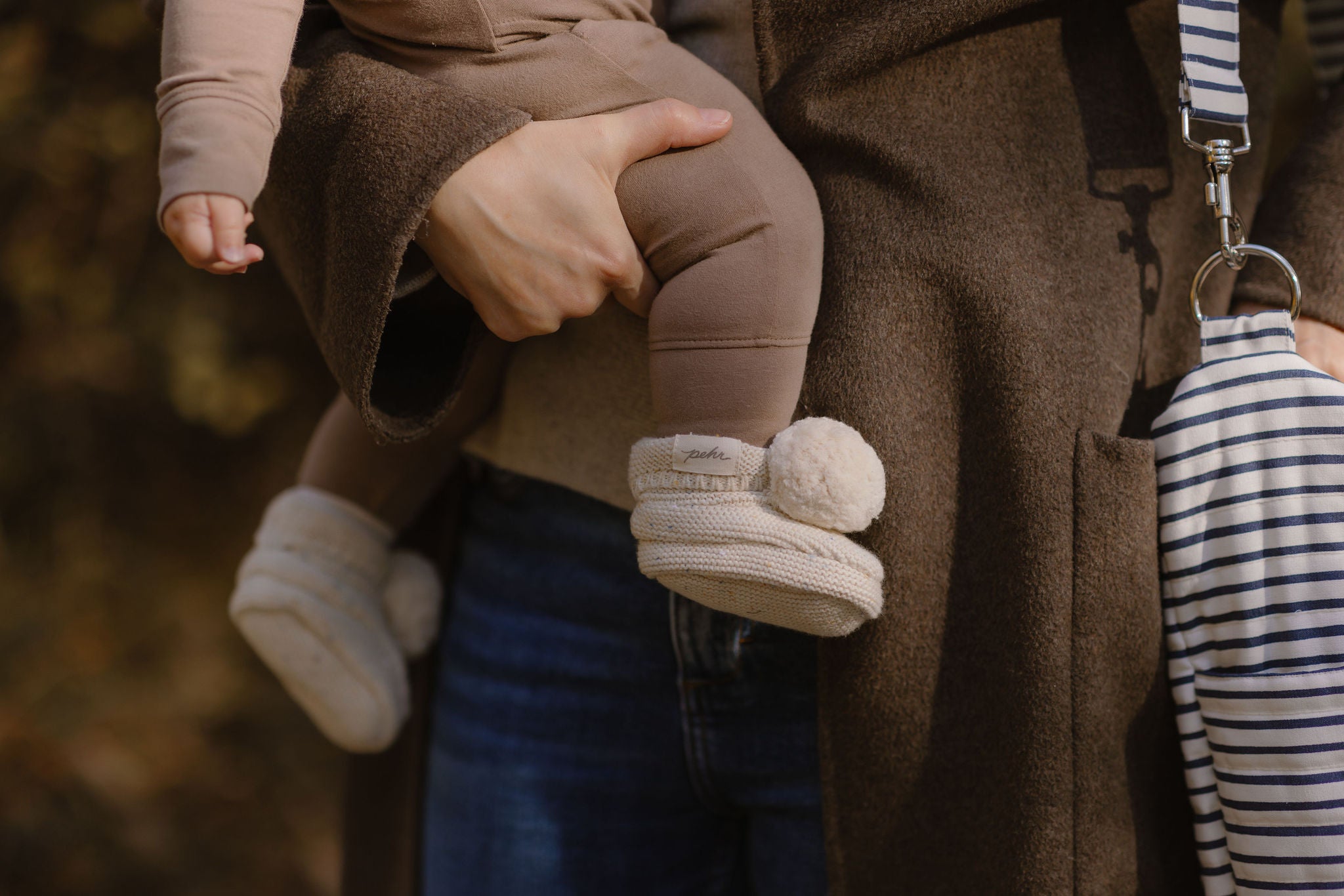 An image of a mom holding her little who is wearing confetti booties.