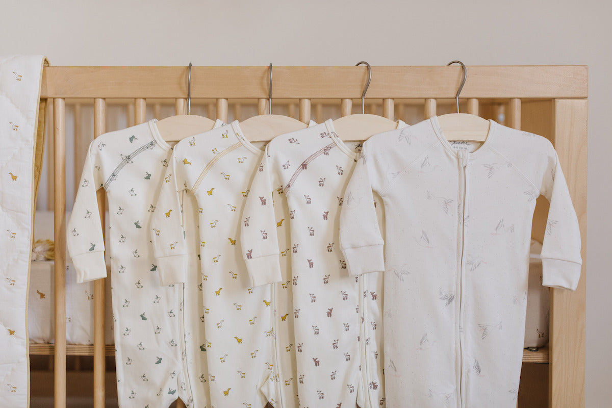 baby onesies hung on crib