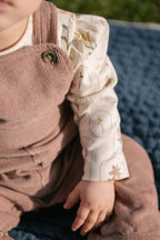 corduroy overall thistle in pinks pattern up close on baby with buttons