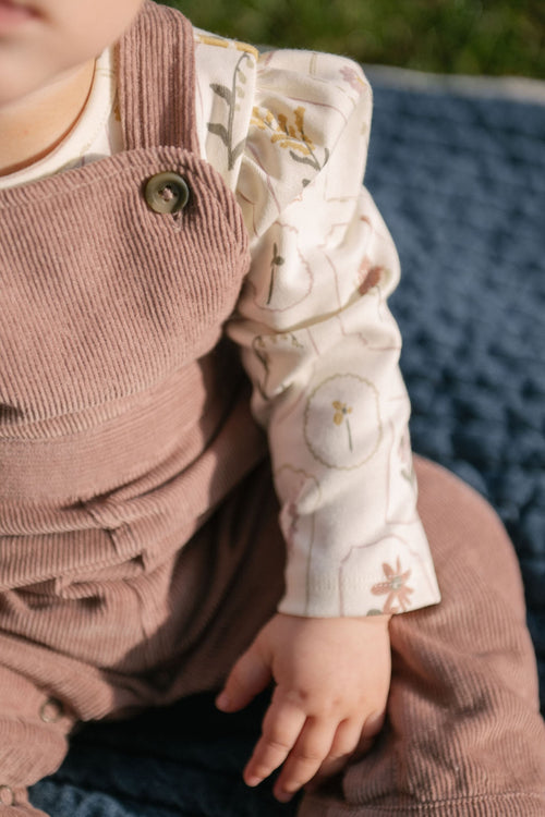 corduroy overall thistle in pinks pattern up close on baby with buttons