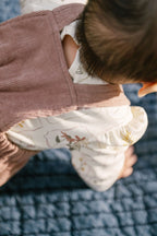 corduroy overall thistle in pinks pattern back of baby up close