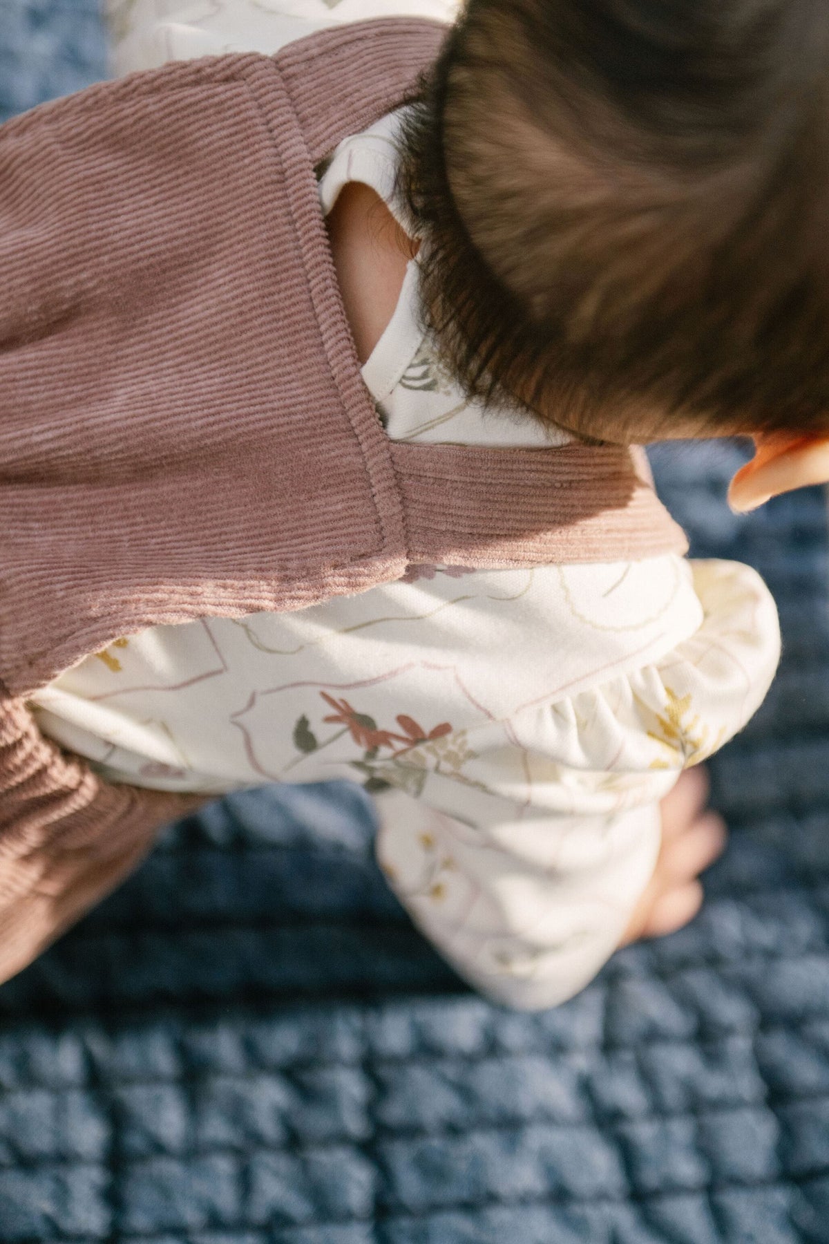 corduroy overall thistle in pinks pattern back of baby up close