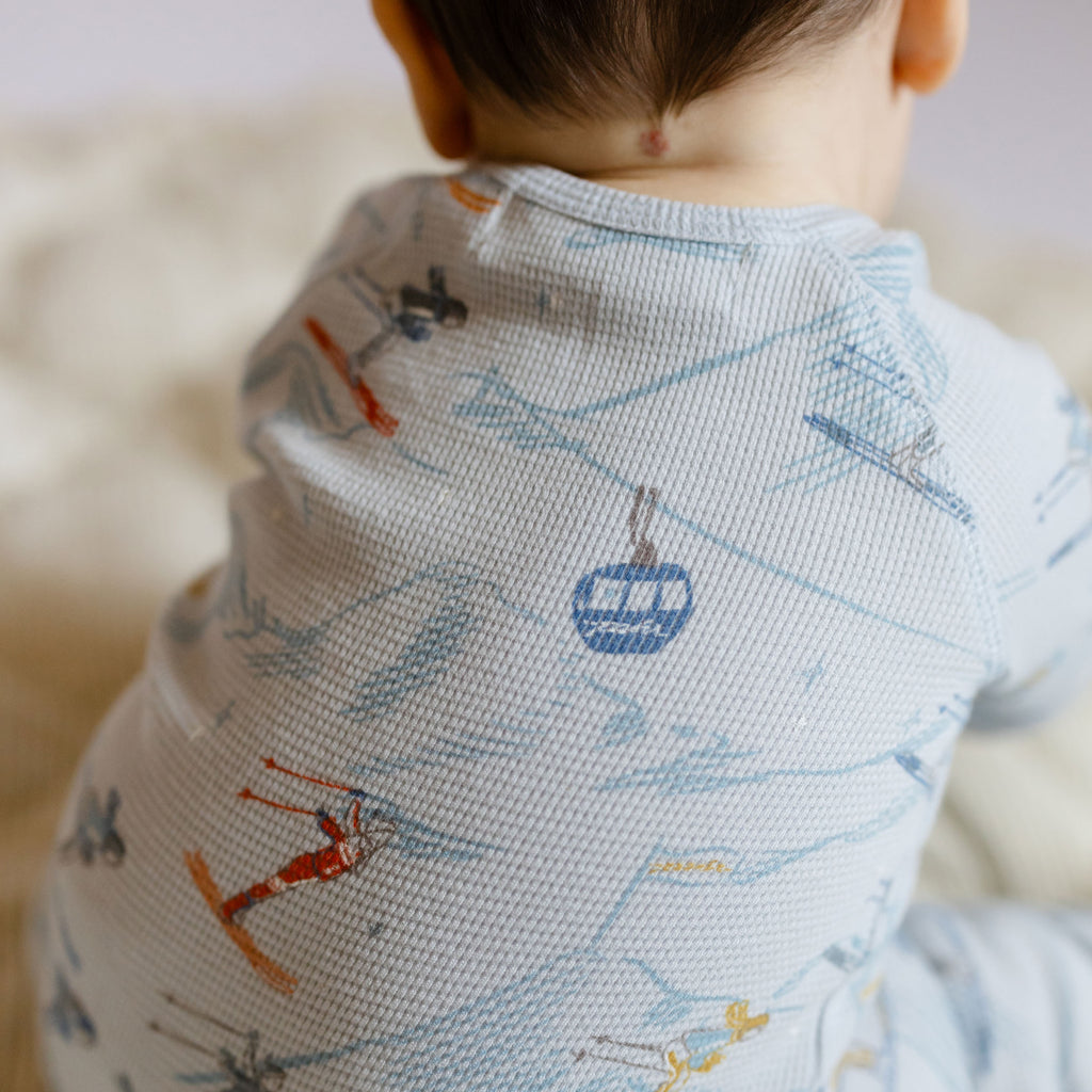 Petit Ski Raglan Romper - On The Slopes- Back of Baby- Close Up- Blue- Ski Print
