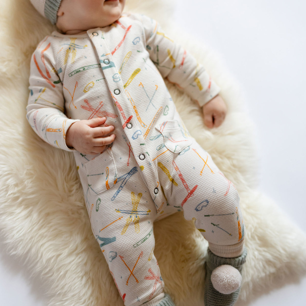 Petit Ski Raglan Romper - Apres- Long Sleeve and Legs- On Baby- White with Colorful Ski print