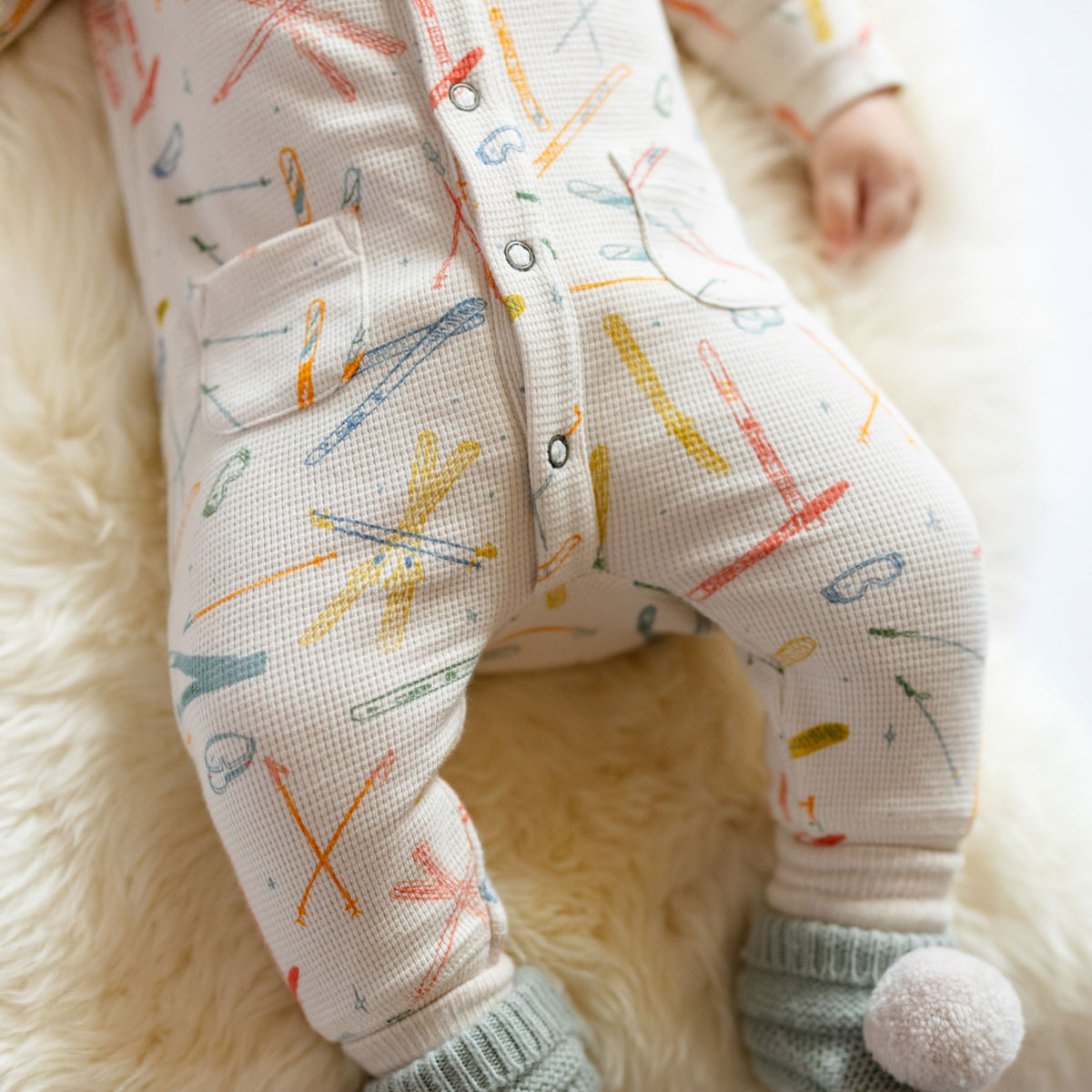 Petit Ski Raglan Romper - Apres- Long Legs- On Baby- White with Colorful Ski Print- Wool Knit Booties with Pom Pom