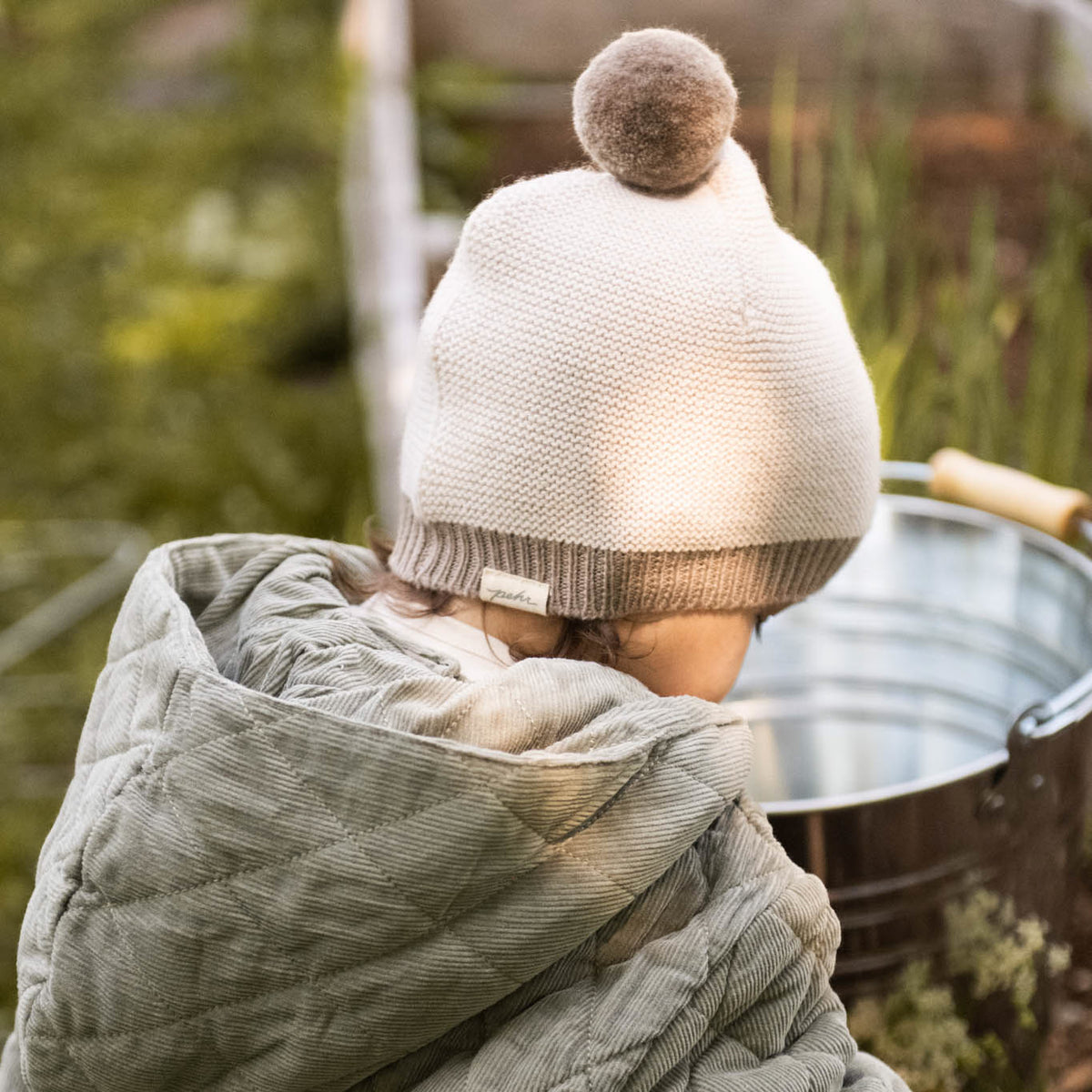 Toddler Wool Knit Hat - Natural - Portobello- Back of Toddler- Beige Furry Ball On Top