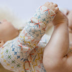 Petit Ski Raglan One-Piece - Snow Patrol- Baby Holding Feet- Colorful Print