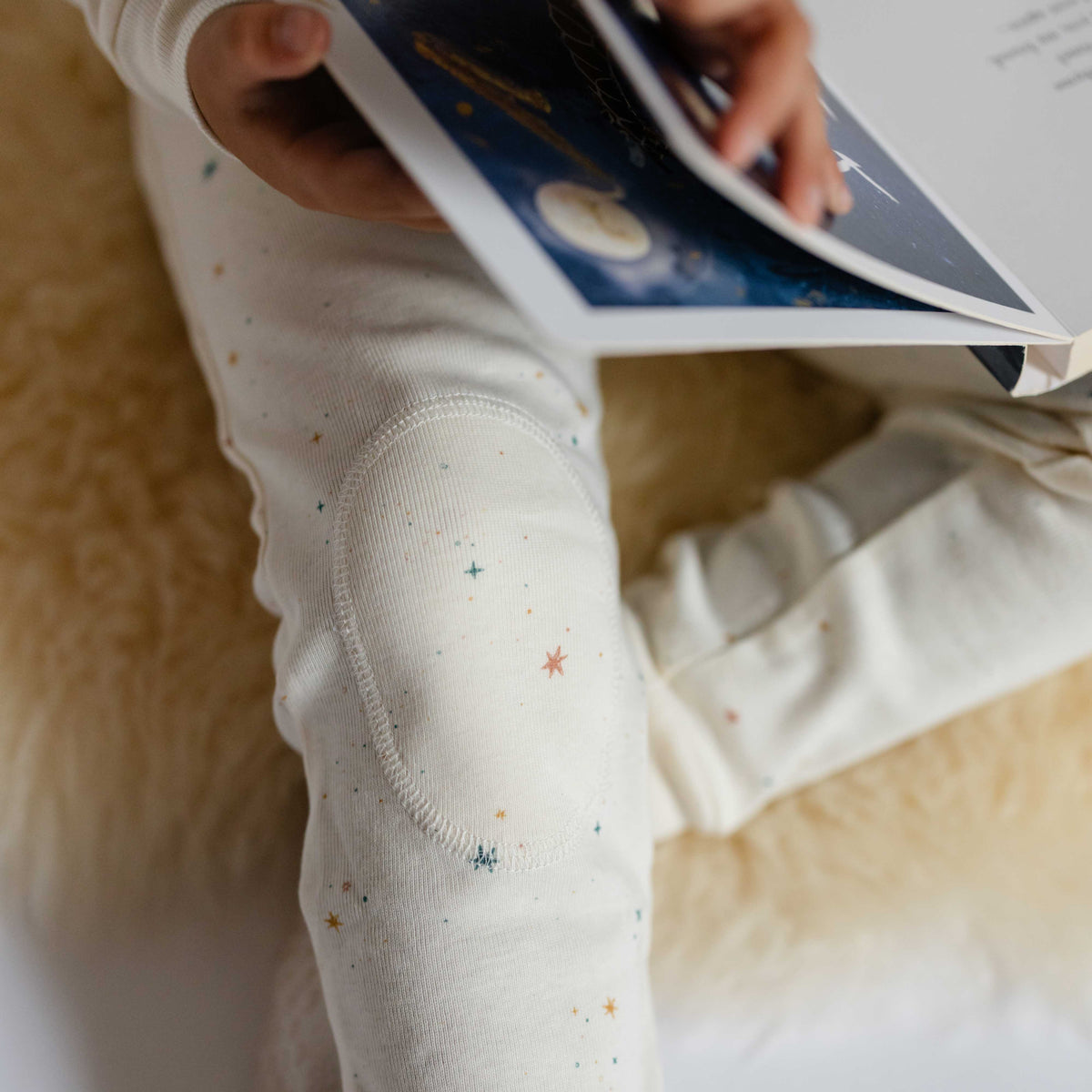 Ribbed Toddler Pajama - Celestial- Toddler Holding Book- White with Little Stars- Close Up Knee Padding