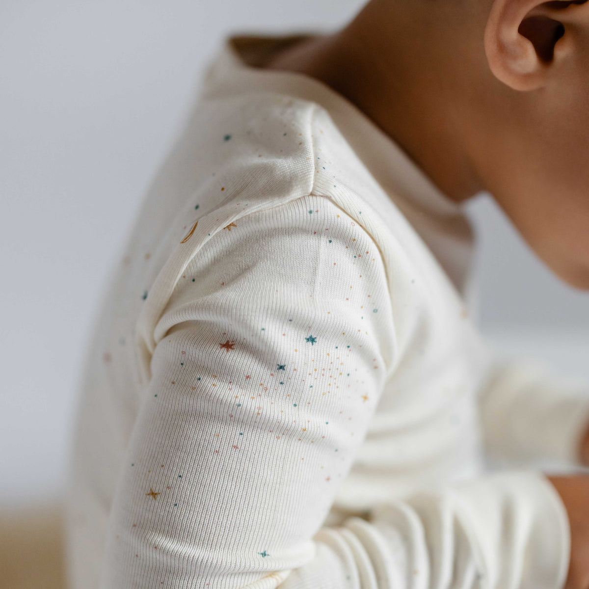 Ribbed Toddler Pajama - Celestial- Toddler Arm Up Close- White with Little Stars
