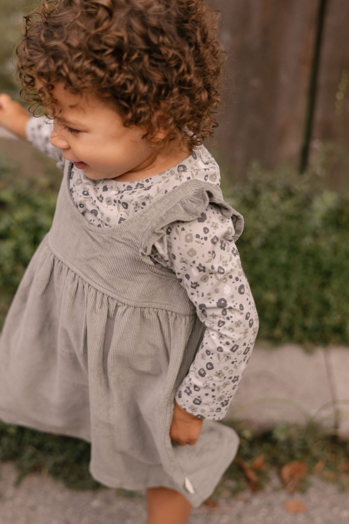corduroy pinafore dress sage in greens pattern on model side ruffle